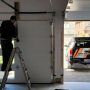 Technician repairing a garage door at night, illustrating 24/7 emergency garage door repair services in 2025