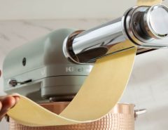 KitchenAid mixer rolling fresh pasta dough into thin golden sheets