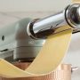 KitchenAid mixer rolling fresh pasta dough into thin golden sheets