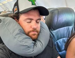 Woman sleeping peacefully on plane with Dot&Dot Twist Pillow wrapped around neck providing perfect posture support