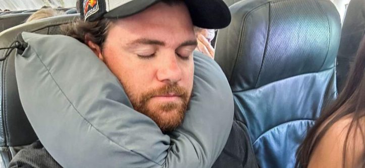 Woman sleeping peacefully on plane with Dot&Dot Twist Pillow wrapped around neck providing perfect posture support