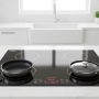 Sleek black induction cooktop with four heating zones in a modern white kitchen
