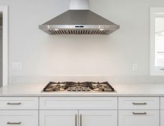 Modern stainless steel 30-inch range hood mounted above gas cooktop in contemporary kitchen with white cabinets