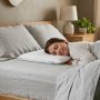 A thin, flat pillow placed on a bed, ideal for stomach sleepers seeking low-loft support