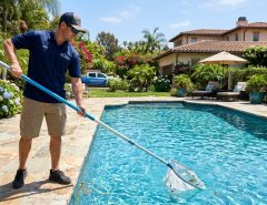Professional skimming debris from a crystal-clear residential swimming pool.