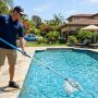 Professional skimming debris from a crystal-clear residential swimming pool.