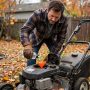 Homeowner adding fuel stabilizer to a lawn mower tank before winter storage outdoors