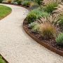 Contemporary garden pathway edged with narrow Corten steel strips containing pale decorative gravel