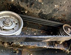 Self-propelled mower drive belt showing cracks and glazing beside pulleys