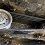 Self-propelled mower drive belt showing cracks and glazing beside pulleys