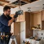Electrician wiring a junction box while installing recessed kitchen lighting