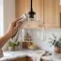 Glass pendant light shade being wiped clean with a microfiber cloth