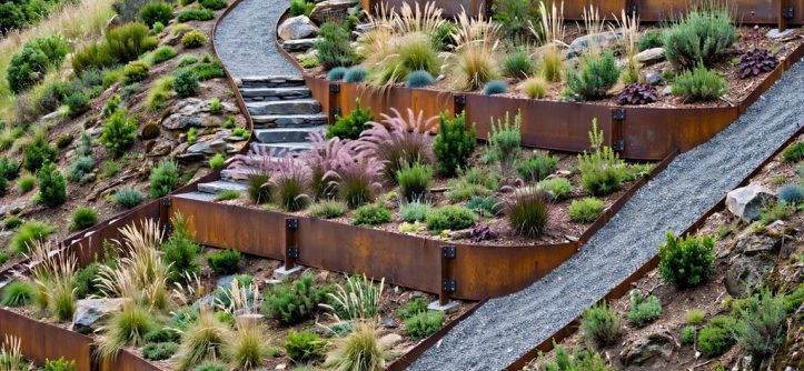 Sloping residential garden with stepped planting beds outlined by weathered steel edging