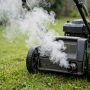 White smoke rising from a lawn mower exhaust during startup outdoors